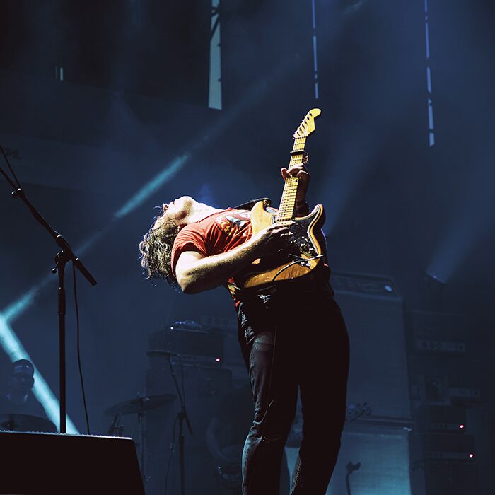 Guitarist performing under stage lights for a continuous learner audience